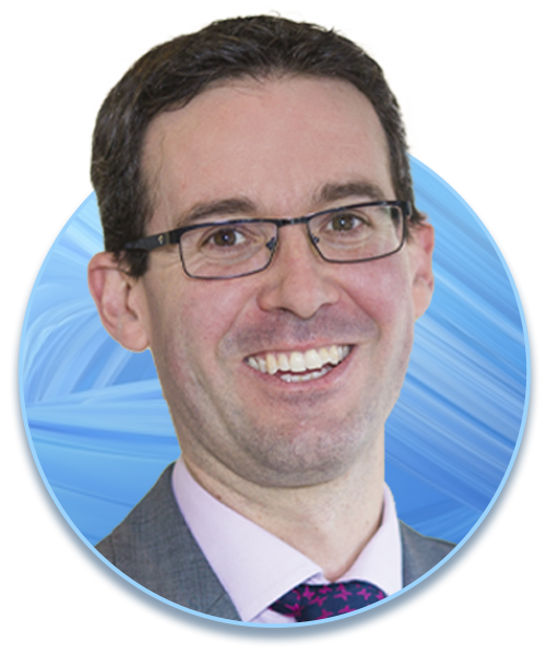 A smiling man with glasses is centered in a circular frame. He is dressed in a suit and tie, set against a soft blue abstract background.