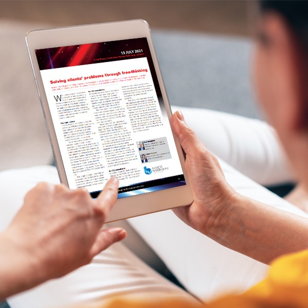 A person is holding a tablet, reading an article titled "Solving clients' problems through free-thinking." The setting is a cozy indoor area with soft colors and textures, suggesting a relaxed environment.
