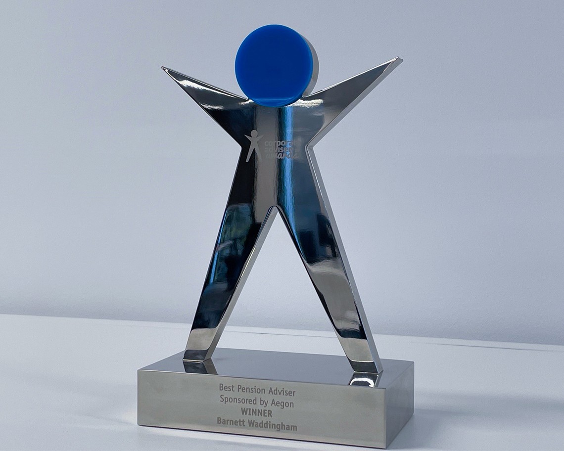 A shiny silver award shaped like a figure with outstretched arms and a blue circular top stands on a white surface. The base reads “Best Pension Adviser Sponsored by Aegon WINNER Barnett Waddingham.”