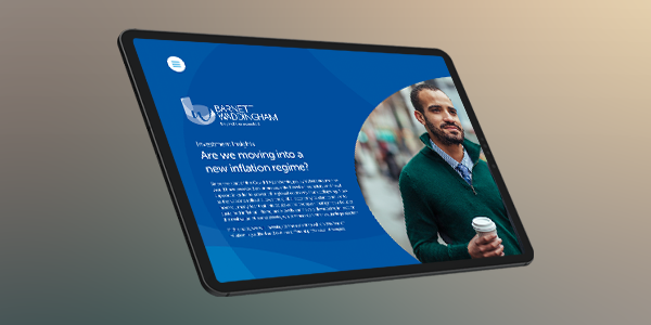 A tablet displays an article titled "Are we moving into a new inflation regime?" alongside an image of a man holding a coffee. The background is softly blurred.