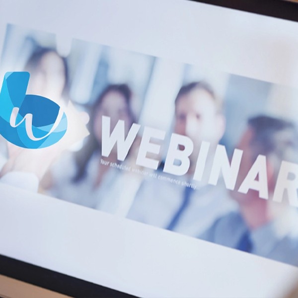 A laptop screen displays a webinar announcement. The word "WEBINAR" is prominently featured, alongside a blue logo. Blurred images of participants are visible in the background. Text: "Your schedule will commence shortly."