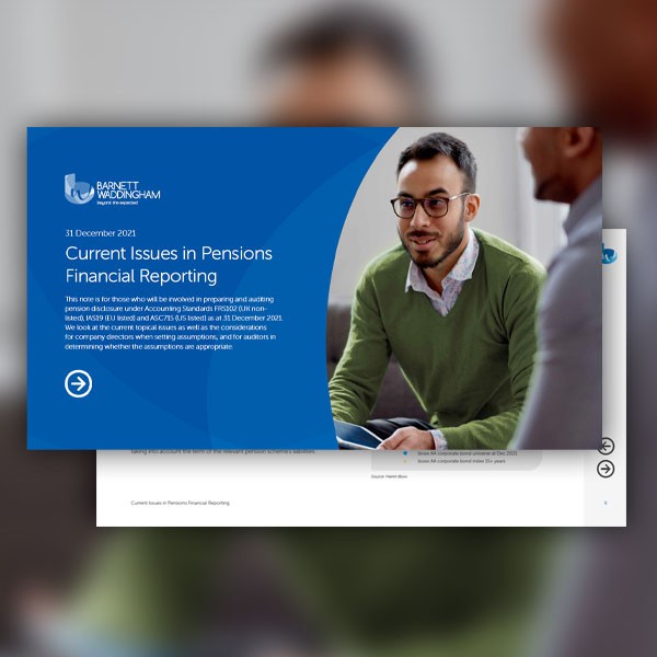 A man with glasses and a green sweater is engaged in conversation, sitting at a table, while a presentation about pension financial reporting is displayed on a digital screen nearby. 

Text: 
31 December 2021  
Current Issues in Pensions Financial Reporti