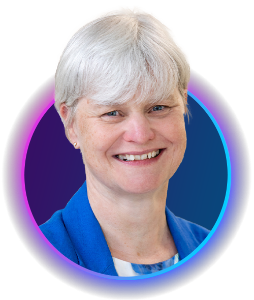 A woman with short, gray hair smiles warmly. She wears a blue blazer over a light-colored shirt. The background features a gradient with colors transitioning from dark to light, creating a vibrant effect.