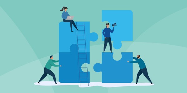 Four people interact with large puzzle pieces in a light green space. One person is on a ladder working on a piece, while another holds a megaphone. Two others are arranging pieces together.