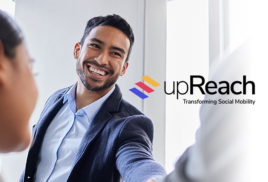 A smiling man in formal attire shakes hands with another person, conveying a positive interaction in a bright, modern office setting. The logo "upReach" appears in the corner, with the tagline "Transforming Social Mobility."