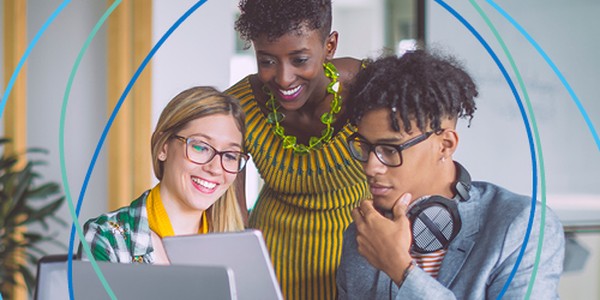 Three individuals are engaged in a collaborative task at a laptop. They are smiling and discussing something displayed on the screen in a modern, well-lit office environment.