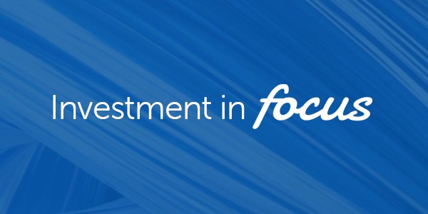 White text reads, "Investment in focus," against a vibrant blue background with abstract wave patterns, creating a modern, dynamic visual effect that emphasizes clarity and concentration on investment themes.
