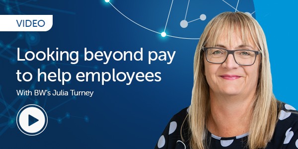 A woman with glasses and long blonde hair discusses employee support beyond monetary compensation. She is set against a blue, technology-themed background with connecting nodes and a play button icon. Text mentions a video with Julia Turney.