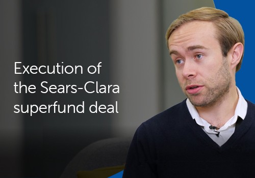 A man in a dark sweater speaks, discussing the execution of the Sears-Clara superfund deal, while seated in a modern, softly lit environment with muted colors.