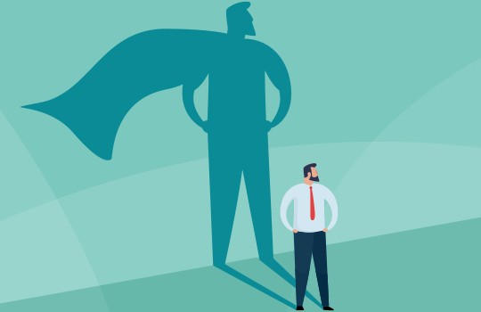 A man in a business suit stands confidently, gazing forward. His shadow projects the image of a superhero with a cape, suggesting strength and inspiration in a light blue background.