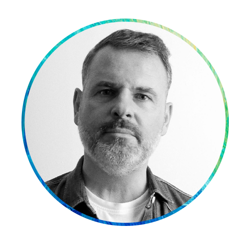 A man with a short beard and slightly gray hair gazes directly at the viewer. He is framed by a circular design featuring colorful, abstract brushstroke patterns.