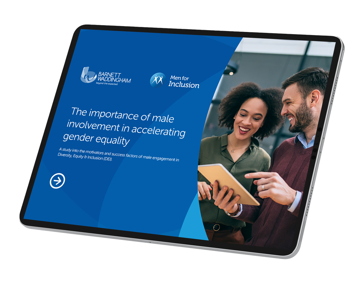 A tablet displays a presentation titled "The importance of male involvement in accelerating gender equality." Two people interact, smiling and discussing content in a modern indoor setting.