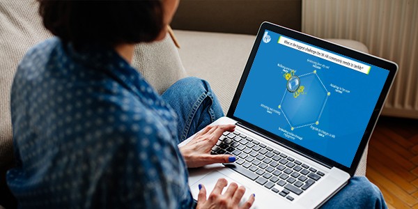 A person sits on a sofa, using a laptop to view a colorful infographic featuring a central graphic and connected elements, possibly related to research or analytics.
