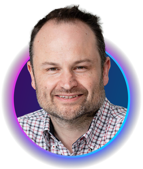 A man with a beard smiles, wearing a checked shirt. He is framed in a circular design with a gradient background that transitions from purple to blue.