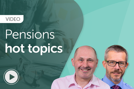 Two men smile while discussing pensions in a professional setting. One is seated, wearing glasses and a blue shirt, while the other stands beside him in a pink shirt. The background features hands writing on paper and a laptop. Text reads: "VIDEO Pensions