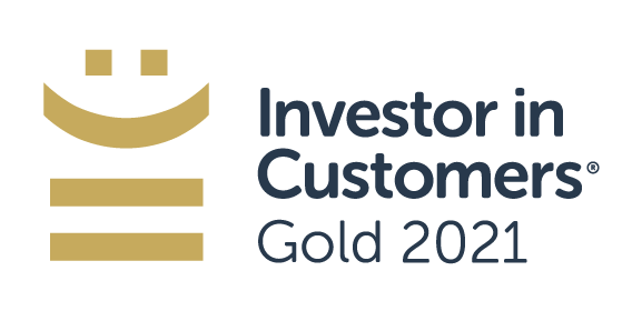 A gold award emblem featuring a smiling stylized face above horizontal lines. Text alongside reads, "Investor in Customers® Gold 2021," signifying recognition in customer investment.
