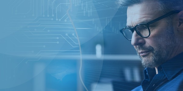A man with glasses is focused on his work, surrounded by a blue-toned environment with abstract technological graphics, suggesting a digital or analytical context.