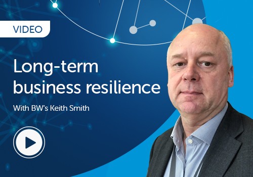 A man with short hair in a blazer speaks about long-term business resilience. The background features abstract connections and a play button icon indicates it's a video.