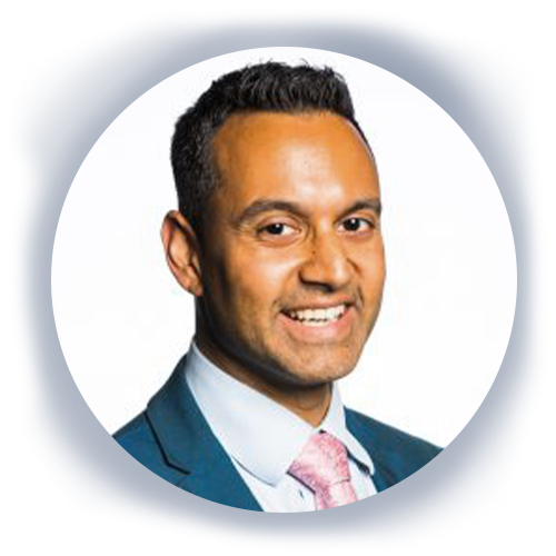 A man with short dark hair and a confident smile wears a blazer with a tie. He is in a professional setting, framed within a circular background that emphasizes his presence.