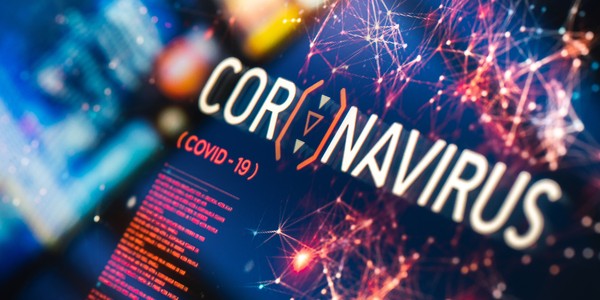 A digital display shows the word “CORONAVIRUS” prominently in large letters, with “(COVID-19)” underneath. A colorful, abstract network pattern surrounds the text, suggesting a high-tech context. Below, text in a smaller font is partially visible.